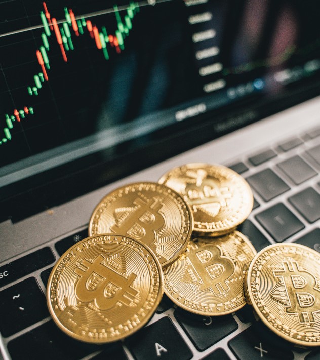 Several gold coins with the BitCoin logo in front of a line graph